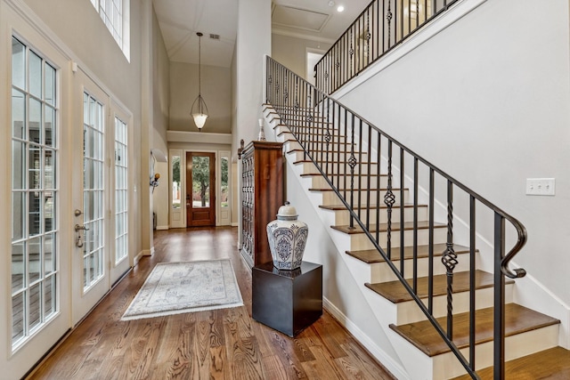 entrance foyer with french doors, a towering ceiling, wood finished floors, baseboards, and stairs