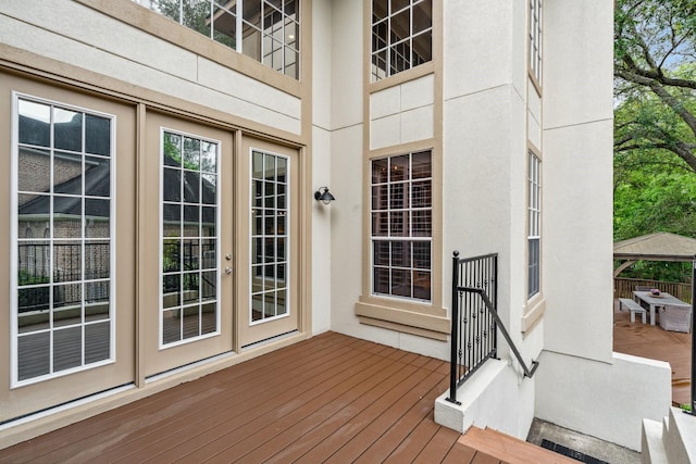 entrance to property with stucco siding, french doors, and a wooden deck