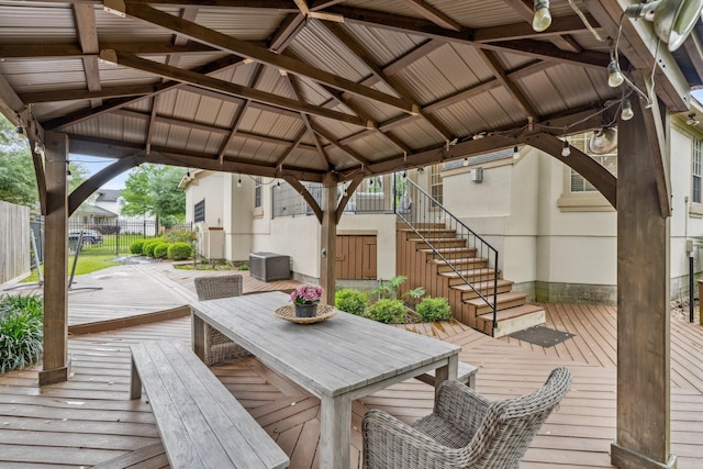 wooden deck with stairway, a gazebo, fence, and outdoor dining space