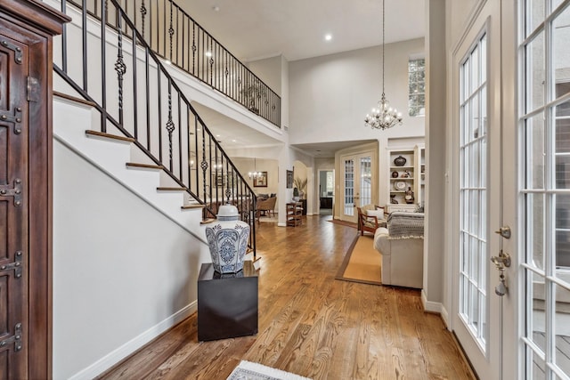 entrance foyer with a chandelier, french doors, stairway, and a towering ceiling