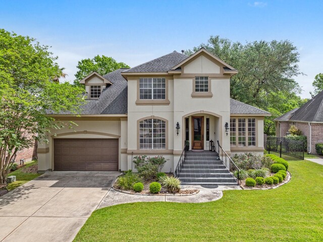 view of front of house featuring driveway, a shingled roof, a front yard, and stucco siding