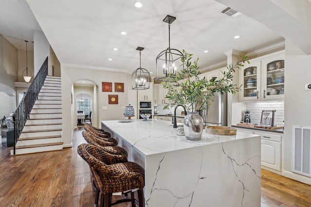 kitchen with arched walkways, black microwave, recessed lighting, and visible vents