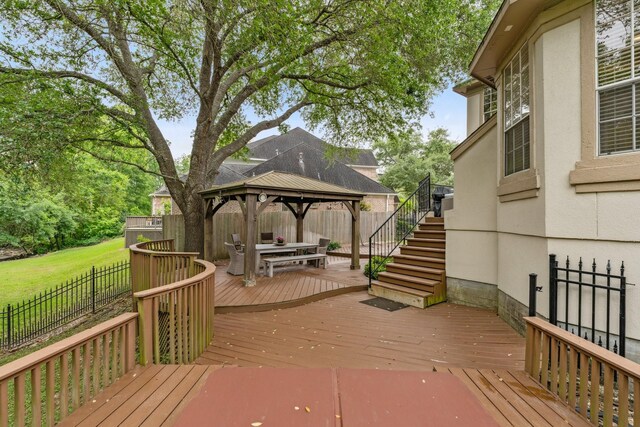 wooden terrace with a fenced backyard, a gazebo, and stairway