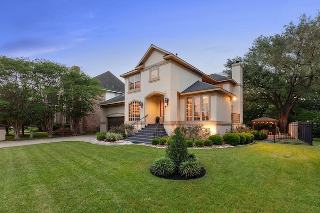 mediterranean / spanish-style home featuring a front lawn, stucco siding, a chimney, concrete driveway, and a gazebo