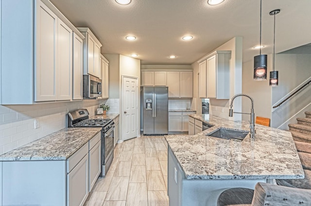 kitchen featuring appliances with stainless steel finishes, light stone counters, a sink, a kitchen breakfast bar, and a peninsula