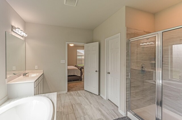 ensuite bathroom with vanity, a tub, baseboards, visible vents, and a stall shower