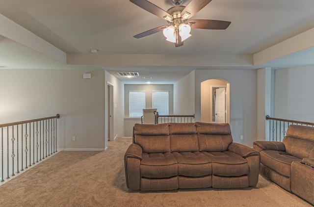 carpeted living room with arched walkways, ceiling fan, visible vents, and baseboards