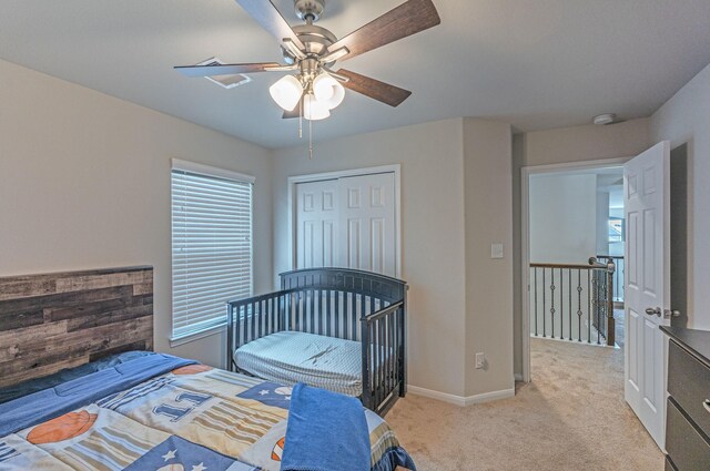 bedroom featuring baseboards, light carpet, multiple windows, and a closet