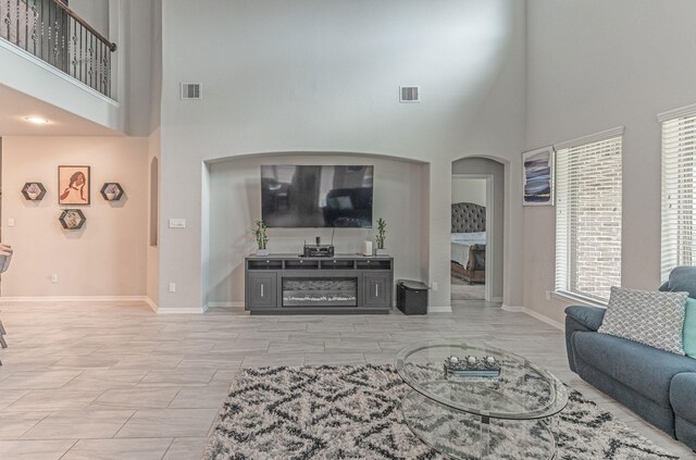 living area with arched walkways, visible vents, and a towering ceiling