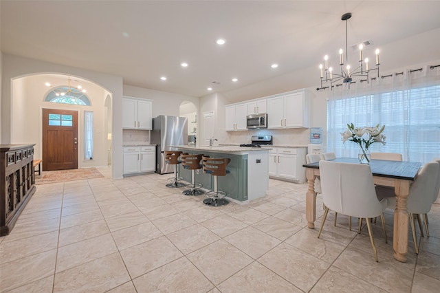 kitchen featuring light tile patterned flooring, appliances with stainless steel finishes, a chandelier, recessed lighting, and a kitchen bar