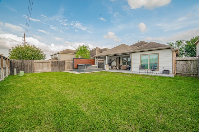 back of property with a fenced backyard, a hot tub, a patio area, and a yard
