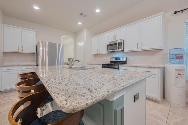 kitchen featuring visible vents, a sink, light tile patterned floors, stainless steel appliances, and an island with sink
