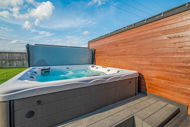 deck featuring a hot tub and fence
