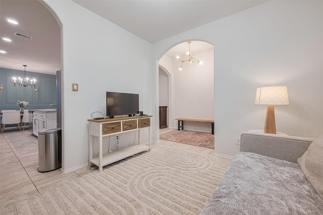 living room with visible vents, arched walkways, light tile patterned floors, and a chandelier