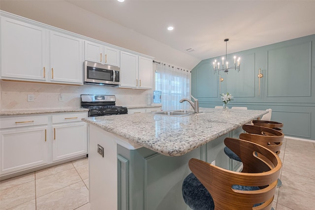 kitchen with white cabinets, an inviting chandelier, a sink, an island with sink, and stainless steel appliances