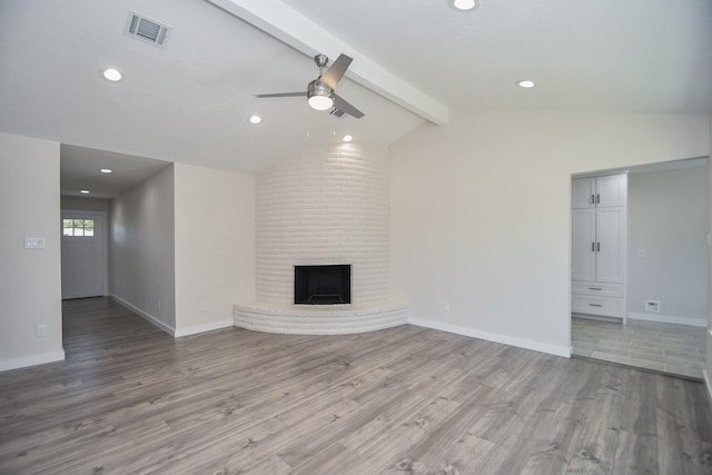 unfurnished living room featuring ceiling fan, lofted ceiling with beams, light wood finished floors, a fireplace, and visible vents