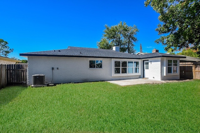 rear view of house with a chimney, a lawn, a patio area, central AC, and fence