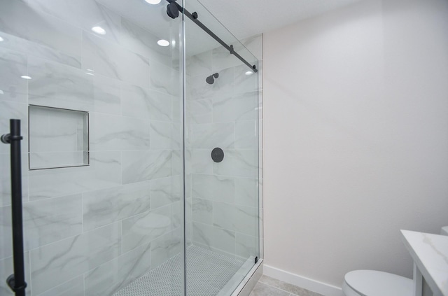 bathroom with vanity, toilet, tile patterned floors, baseboards, and a shower stall