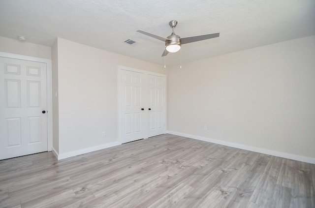 unfurnished bedroom featuring light wood-style flooring, a ceiling fan, baseboards, visible vents, and a closet