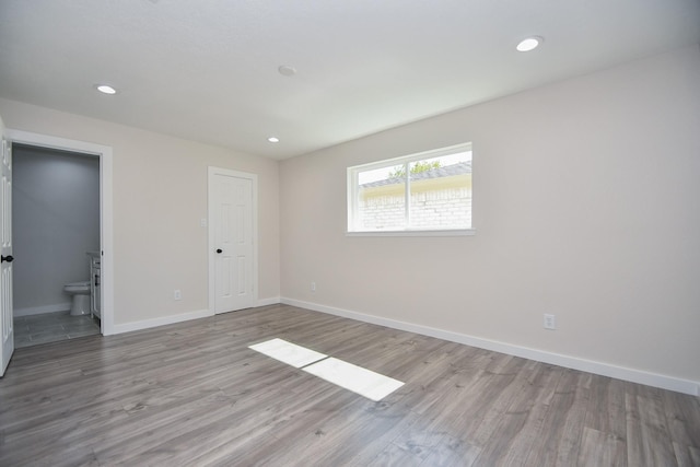 spare room with baseboards, recessed lighting, and wood finished floors
