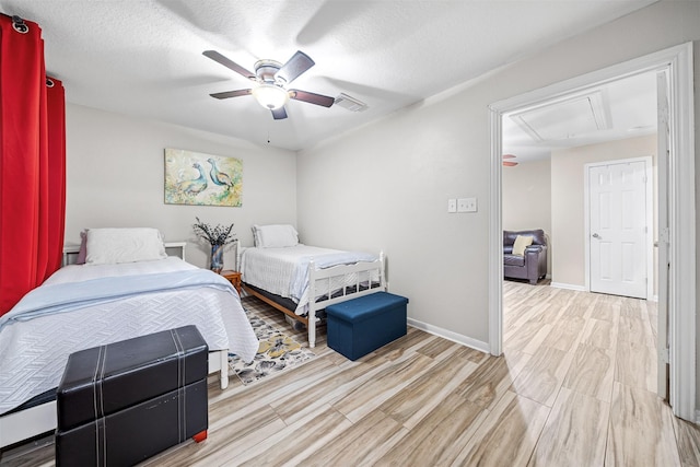 bedroom with visible vents, wood finished floors, baseboards, attic access, and a ceiling fan
