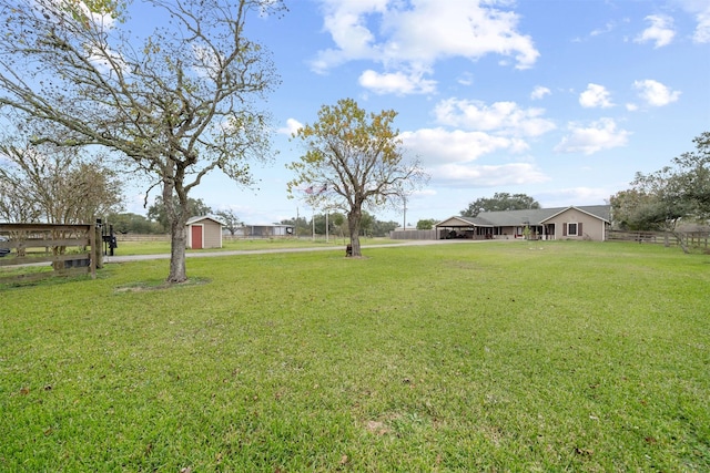 view of yard featuring an outdoor structure, fence, and a storage shed