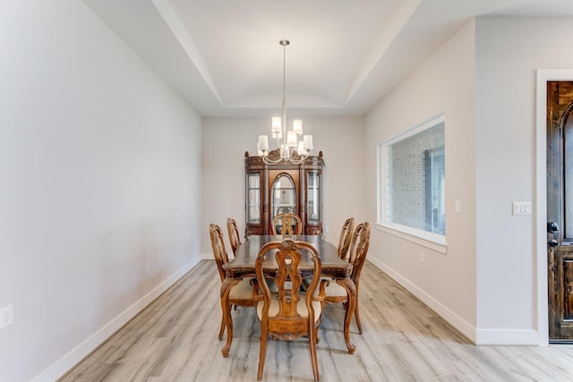 dining room with light wood-style floors, baseboards, a notable chandelier, and vaulted ceiling