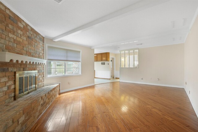 711 Rosewood Dr, Shenandoah, TX 77381 - unfurnished living room featuring healthy amount of natural light, light wood finished floors, a fireplace, baseboards, and beam ceiling