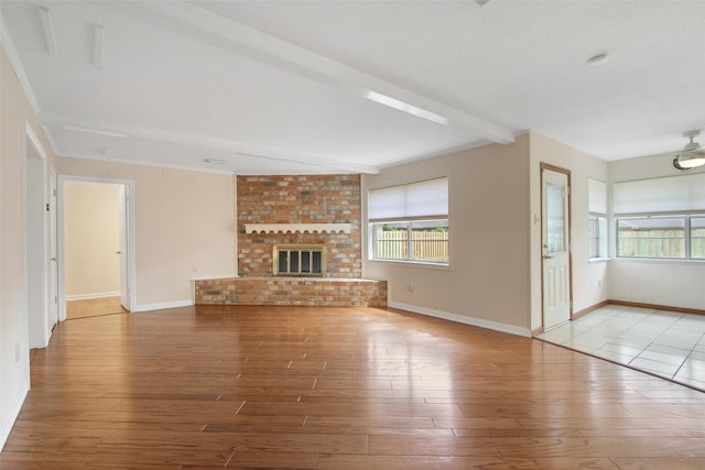 711 Rosewood Dr, Shenandoah, TX 77381 - unfurnished living room with wood finished floors, plenty of natural light, baseboards, and beamed ceiling