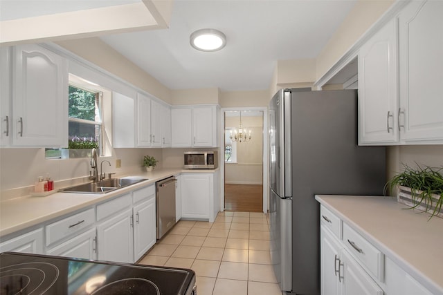 711 Rosewood Dr, Shenandoah, TX 77381 - kitchen with stainless steel appliances, a sink, white cabinets, light tile patterned floors, and a chandelier