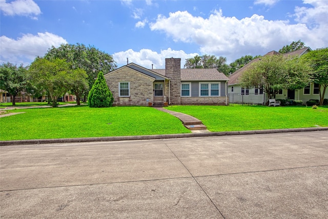 view of front of property featuring a chimney, a front lawn, and stone siding