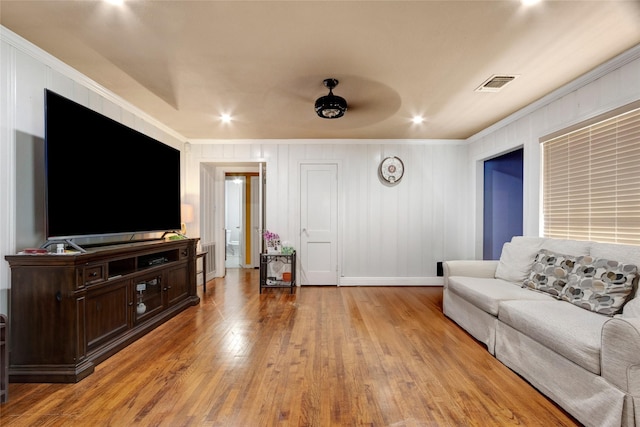 living room with visible vents, baseboards, light wood finished floors, ornamental molding, and recessed lighting