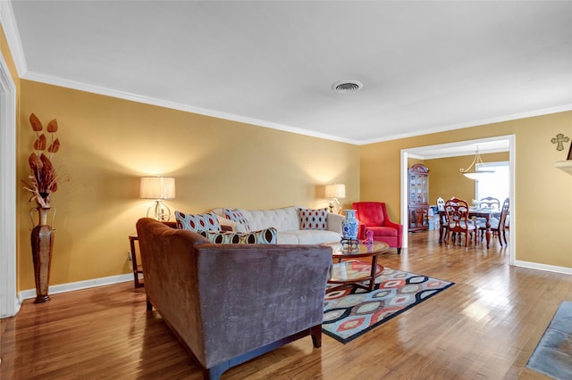living area featuring baseboards, visible vents, ornamental molding, and wood finished floors