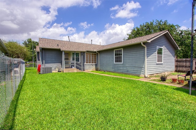 rear view of property featuring a lawn, a shingled roof, a fenced backyard, and central air condition unit
