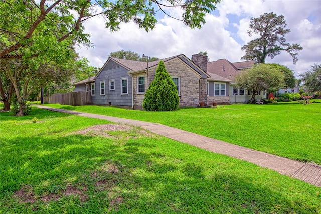 ranch-style home with stone siding, fence, a chimney, and a front yard