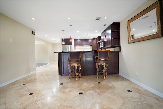 bar with arched walkways, baseboards, visible vents, pendant lighting, and a bar