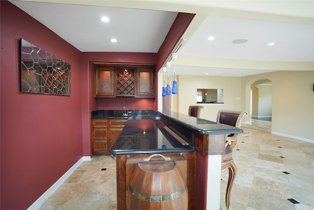 bar with arched walkways, wet bar, recessed lighting, and baseboards