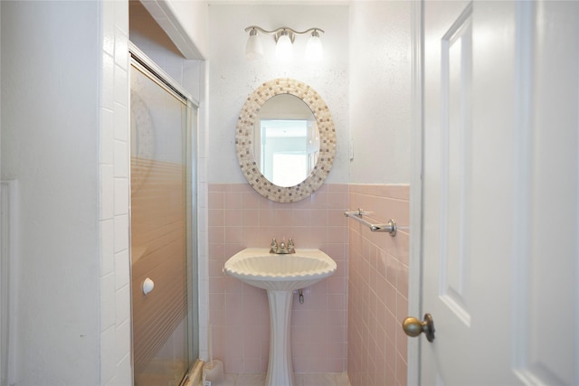 bathroom with tile walls, a wainscoted wall, and a shower stall