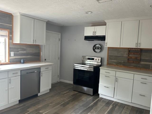 19101 Oak Canyon Dr, Conroe, TX 77385 - kitchen with dark wood-style flooring, light countertops, a textured ceiling, under cabinet range hood, and appliances with stainless steel finishes
