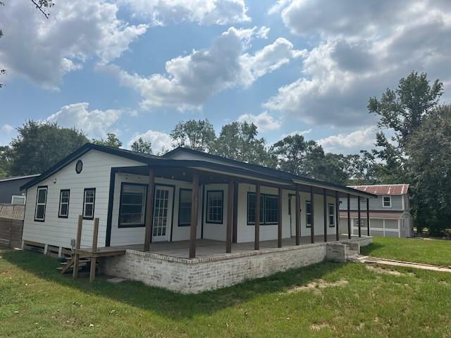19101 Oak Canyon Dr, Conroe, TX 77385 - back of property featuring a lawn and covered porch