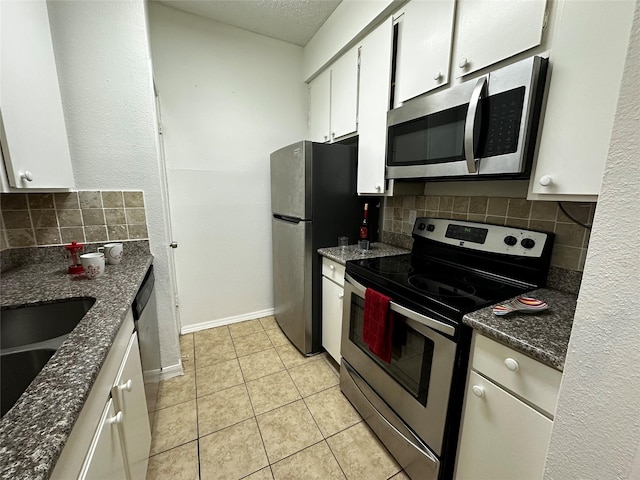 10047 Westpark Dr Unit 73, Houston, TX 77042 - kitchen with decorative backsplash, appliances with stainless steel finishes, light tile patterned floors, baseboards, and white cabinetry