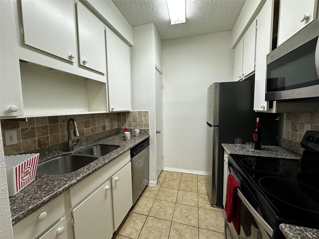 10047 Westpark Dr Unit 73, Houston, TX 77042 - kitchen featuring white cabinets, a sink, a textured ceiling, stainless steel appliances, and decorative backsplash