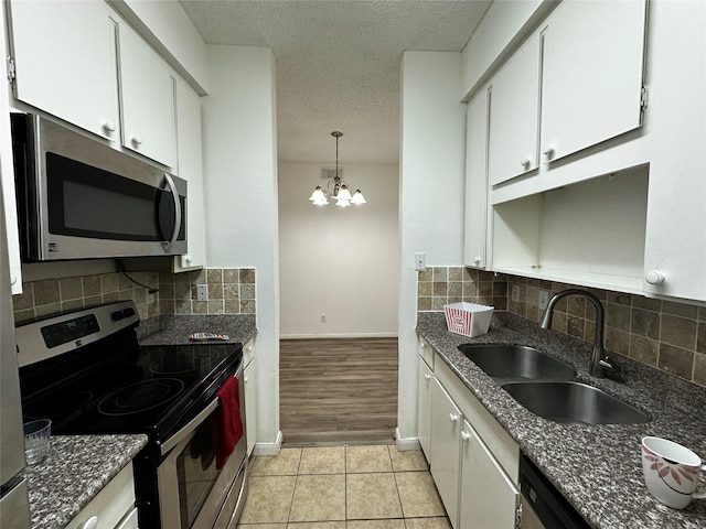 10047 Westpark Dr Unit 73, Houston, TX 77042 - kitchen featuring a textured ceiling, appliances with stainless steel finishes, a sink, a chandelier, and white cabinetry