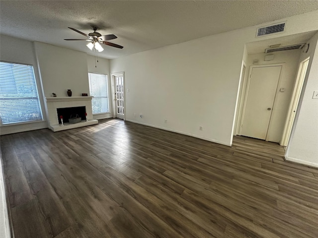 10047 Westpark Dr Unit 73, Houston, TX 77042 - unfurnished living room featuring ceiling fan, a textured ceiling, visible vents, dark wood finished floors, and a fireplace with raised hearth