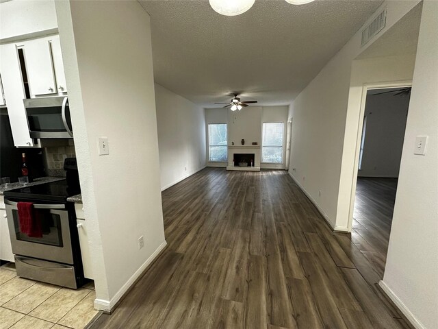 10047 Westpark Dr Unit 73, Houston, TX 77042 - interior space featuring visible vents, wood finished floors, ceiling fan, a fireplace with raised hearth, and appliances with stainless steel finishes