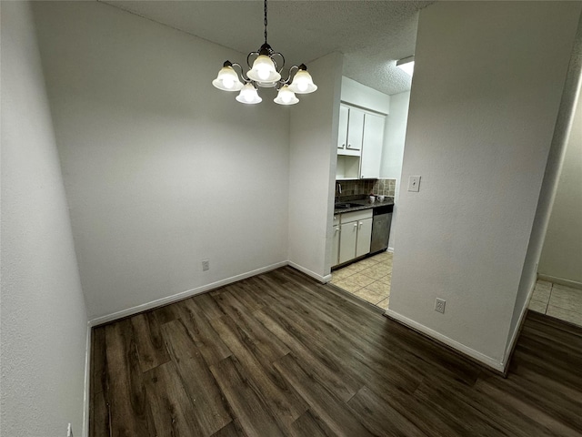 10047 Westpark Dr Unit 73, Houston, TX 77042 - unfurnished dining area featuring a sink, baseboards, wood finished floors, and a notable chandelier