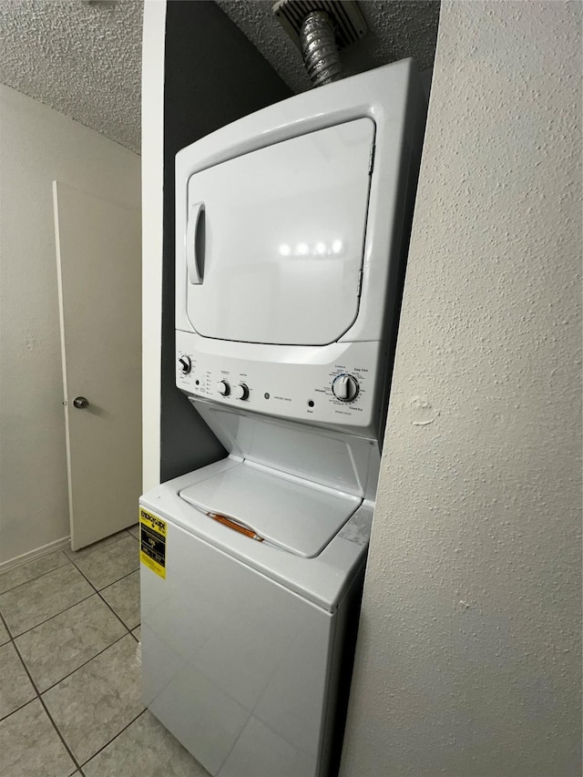 10047 Westpark Dr Unit 73, Houston, TX 77042 - clothes washing area with light tile patterned floors, a textured wall, stacked washer and clothes dryer, and laundry area