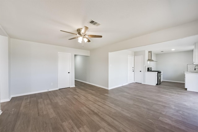 unfurnished living room with dark wood-style flooring, a ceiling fan, baseboards, and visible vents