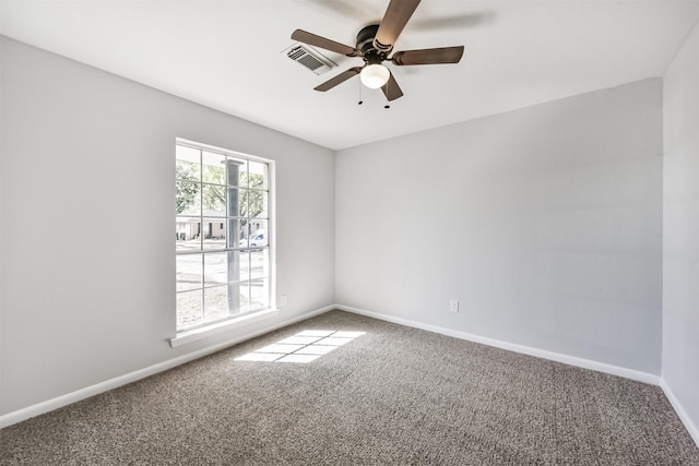 carpeted empty room with baseboards, a ceiling fan, and visible vents