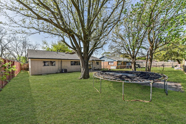 view of yard featuring central AC, a fenced backyard, and a trampoline
